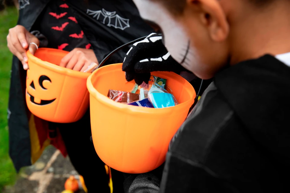 ninos sosteniendo sus cubos de truco o trato